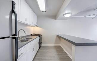 A kitchen with white cabinets and a black refrigerator.
