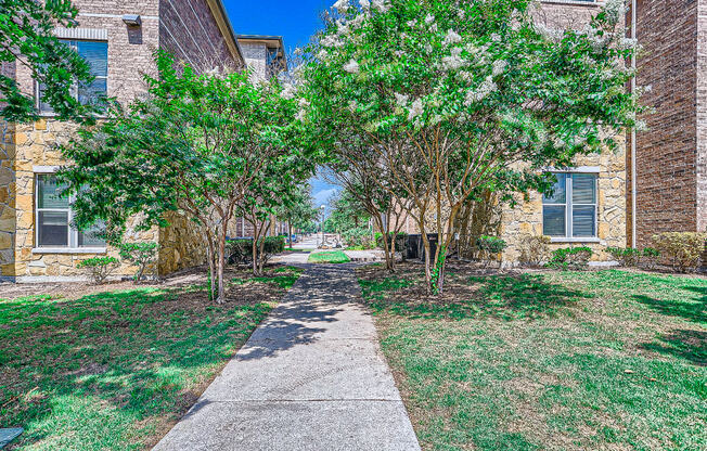 a walkway between two brick buildings with trees at Discovery at Craig Ranch, McKinney, 75070
