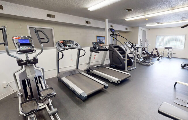 A gym with treadmills, elliptical machines, and other exercise equipment.