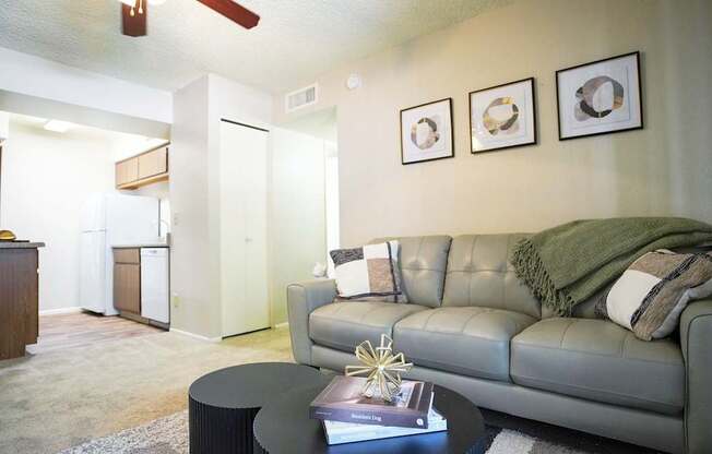 A living room with a grey couch, a coffee table, and a ceiling fan.