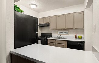 a kitchen with a white counter top and a black refrigerator