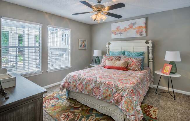 A bedroom with a floral bedspread and a ceiling fan.