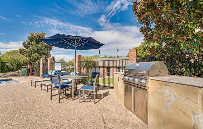 A patio with a table, chairs, and an umbrella.