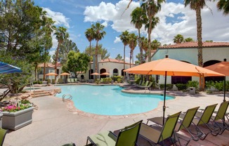 a swimming pool with chairs and umbrellas and a building in the background