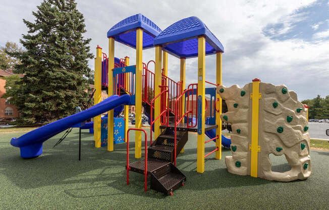 a playground with a blue and yellow play set and a tree
