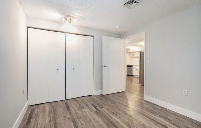 a bedroom with white walls and hardwood floors