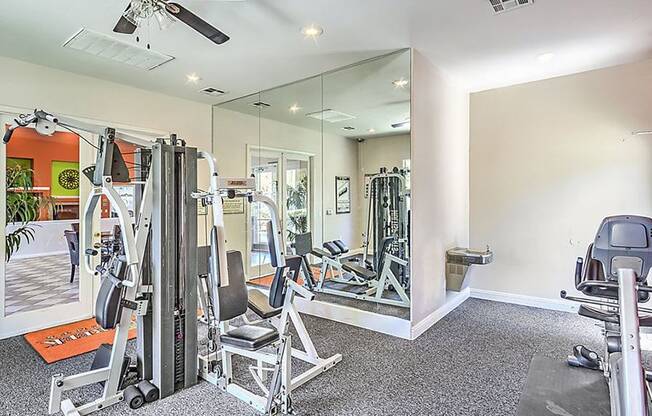 the home gym has a large mirror and plenty of exercise equipment