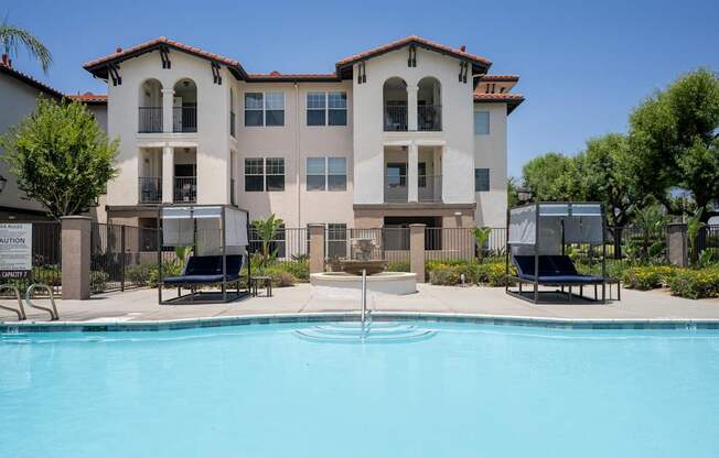 A large white building with a pool in front.