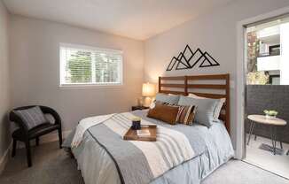 A bedroom with a bed, a chair, and a window.