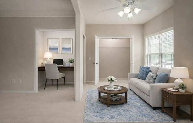 A living room with a couch, a desk, and a ceiling fan.
