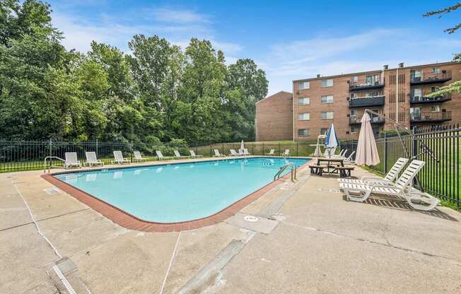 A large outdoor swimming pool surrounded by trees and chairs.