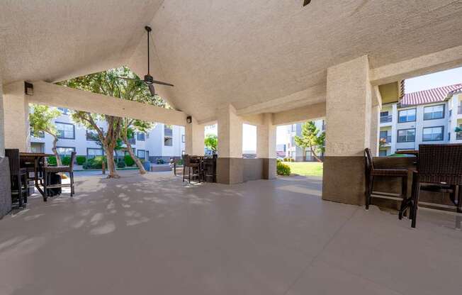 A spacious covered patio area with a ceiling fan and multiple seating options.