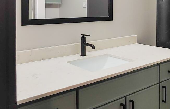 sage vanity with a white quartz countertop