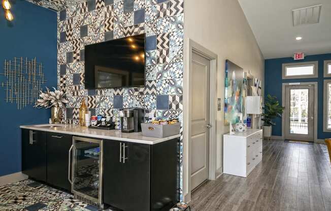 The Retreat at Indian Lake apartments lobby coffee bar with self-serve coffee supplies, black modern cabinets, and mini fridge.