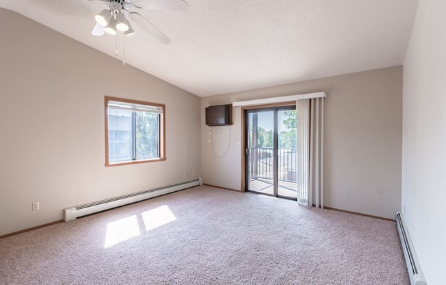 an empty living room with a sliding glass door to a balcony. Fargo, ND Rosegate Apartments