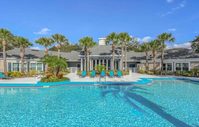 A swimming pool in front of a building with palm trees.