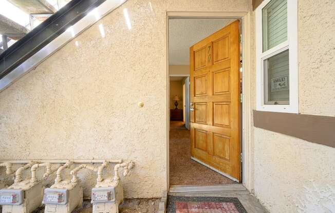 an open door leading to a hallway with a wooden door and white boxes in front of it at Oak Terrace Senior Apts, Hemet California