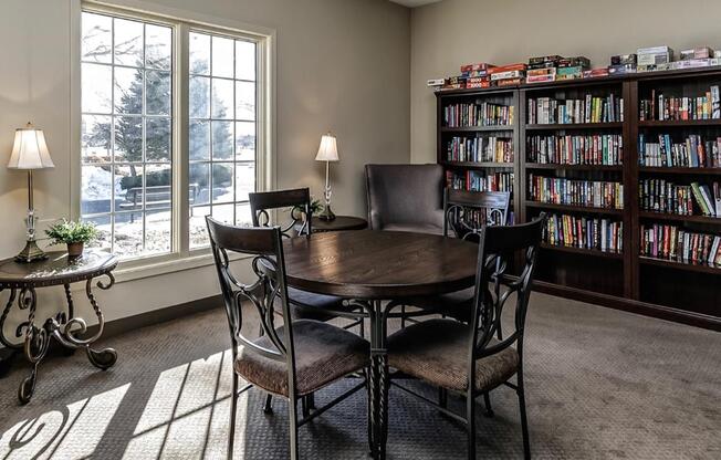 a library with a table and chairs in front of a window