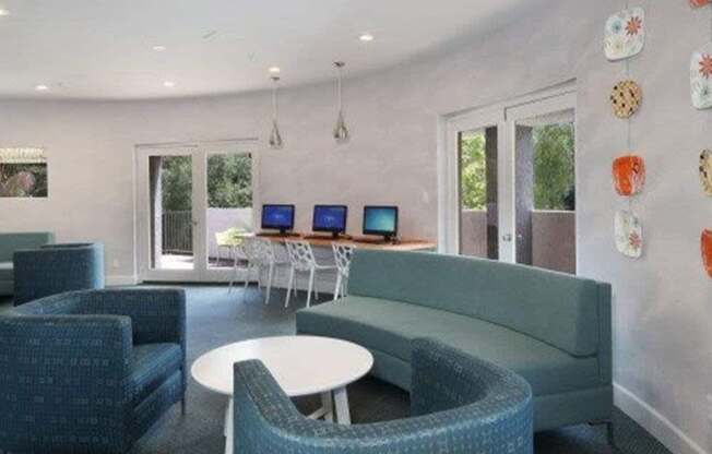 A room with a blue couch, chairs, and tables.