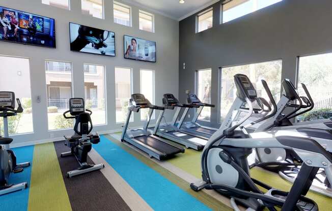 Well equipped fitness center with treadmills, elliptical machines, stationary bikes, and large TV's