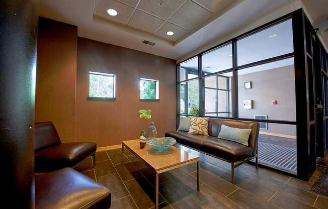 A living room with a brown leather couch, chairs and a coffee table.