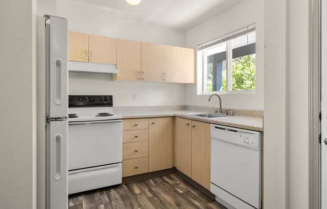 a kitchen with white appliances and wooden cabinets at Mill Pond Apartments, Auburn, WA 98092