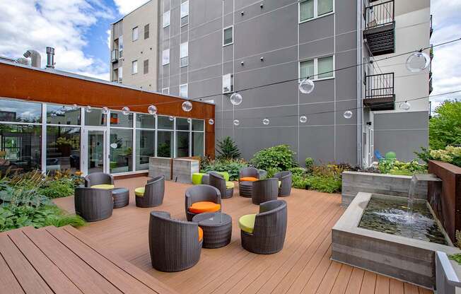 A wooden deck with wicker chairs and a water feature.