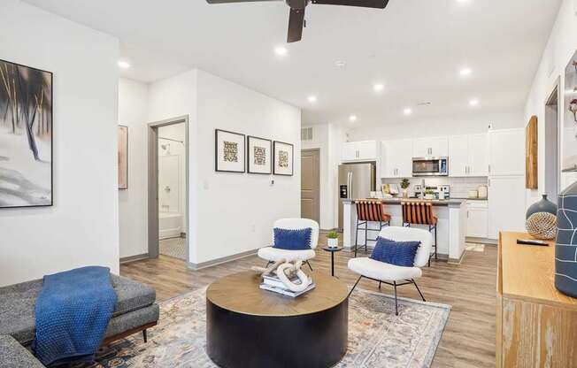 a living room with furniture and a kitchen in the background