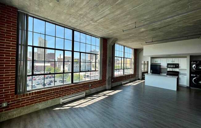 an open living room with large windows and a kitchen in a loft