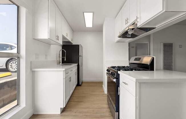 A modern kitchen with white cabinets and black appliances.