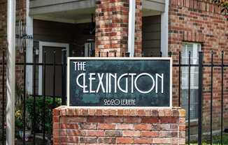 A sign that says "The Lexington" is in front of a brick building.