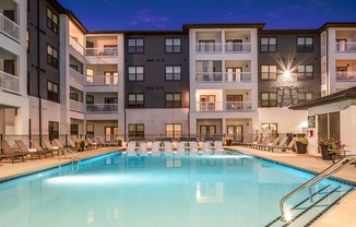 a swimming pool with chaise lounge chairs and a building in the background