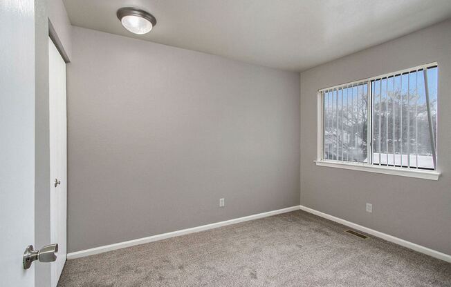 an empty living room with a window and carpet