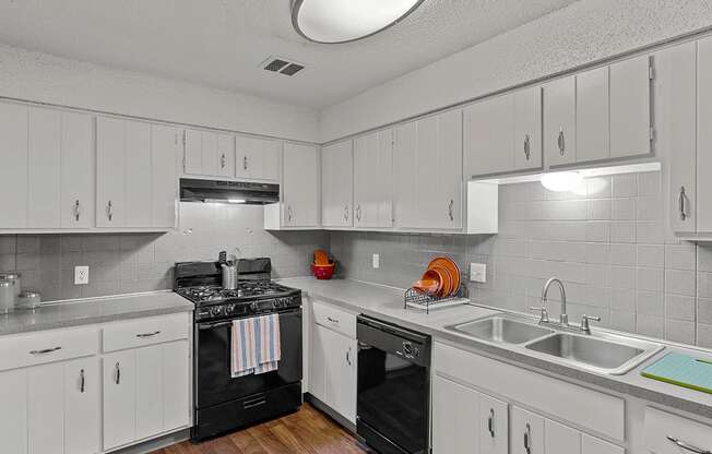 a kitchen with white cabinets and black appliances and a sink