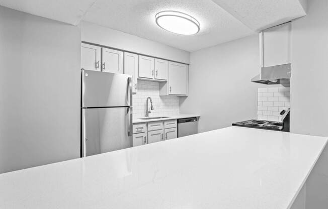 a kitchen with a white counter top and a stainless steel refrigerator