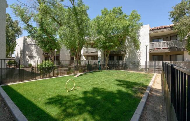 A backyard with a green lawn and a white fence.