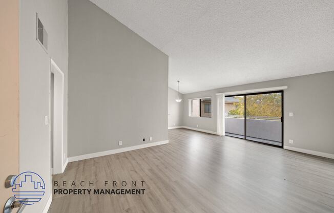 the living room and dining room of an apartment with wood flooring and a balcony