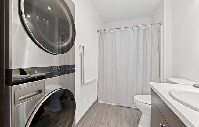 a washer and dryer in a bathroom with a shower and a toilet