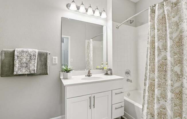 A bathroom with a white sink and a shower with a curtain.