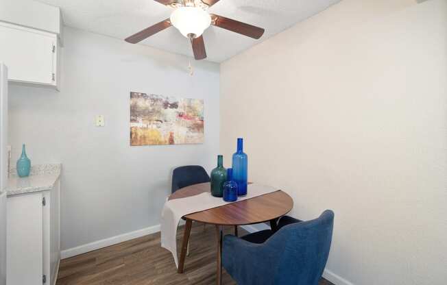 a dining room area with a table and chairs and a ceiling fan