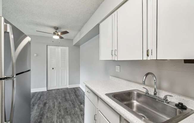 A kitchen with a stainless steel refrigerator, sink, and ceiling fan.