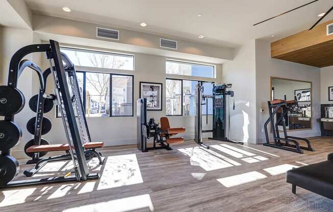 a gym with exercise equipment and windows at the district flats apartments  at Westbury Apartments, Rancho Cucamonga, California