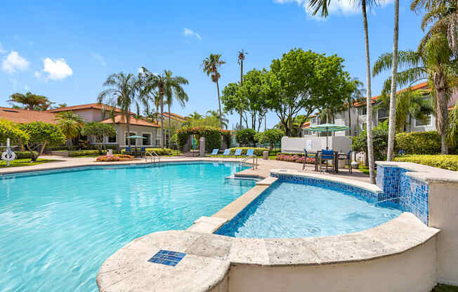 A swimming pool surrounded by palm trees and a building in the background.