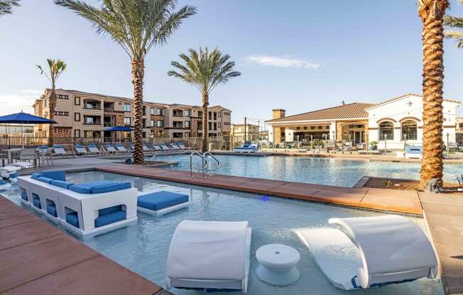 Apartments in Chandler AZ-The Core Chandler Resort-Style Swimming Pool Surrounded by Lounge Chairs, Palm Trees, and a Separate In-Water Seating Area
