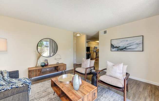 Living room with two tone paint,  Hardwood Inspired Floor, Gray/White Rug, Gray Sofa and Round Mirror at Silverstone Apartments, Davis, CA, 95618