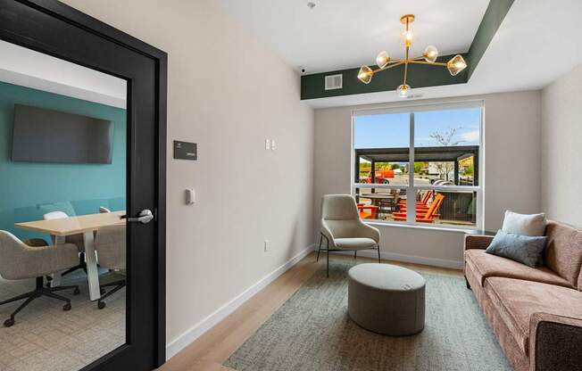 A room with a couch, chair, and table with a view of the outside.