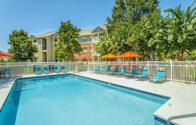 a swimming pool with blue chairs and orange umbrellas