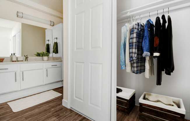 a bathroom with a white door and a closet with clothes hanging