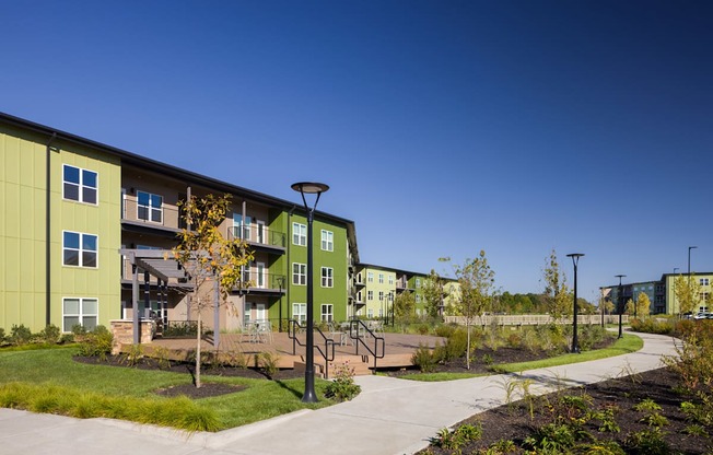 A green apartment complex with a clear blue sky in the background.