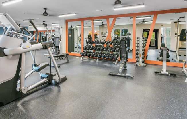 a gym with weights and cardio equipment in a building with orange walls